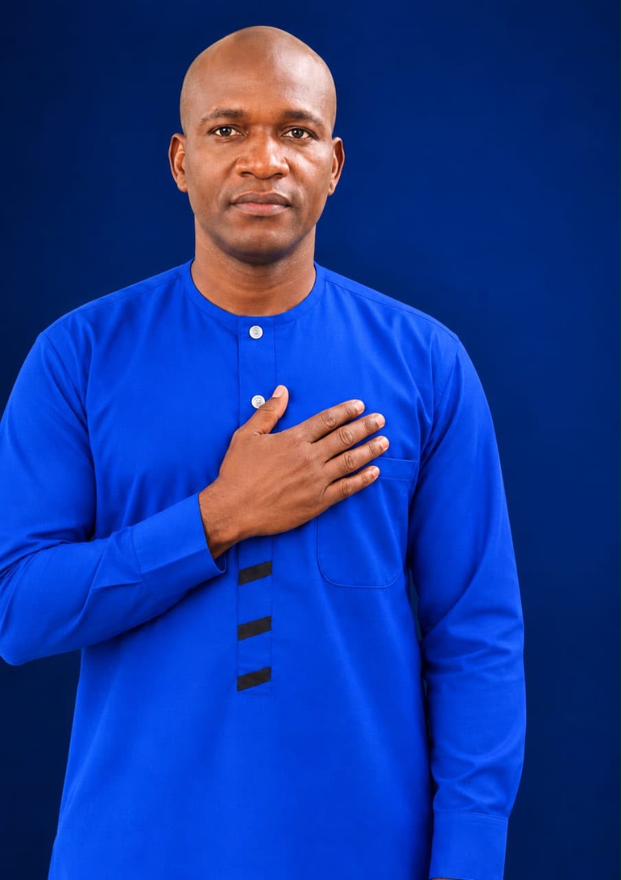 Portrait de Mamadou Kille Konaté en tenue bleue, la main sur le cœur